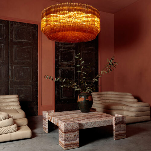 Grande Amber Amaro - large amber drum triedri chandelier in mid-century Murano glass style hanging over a red square marble coffee table